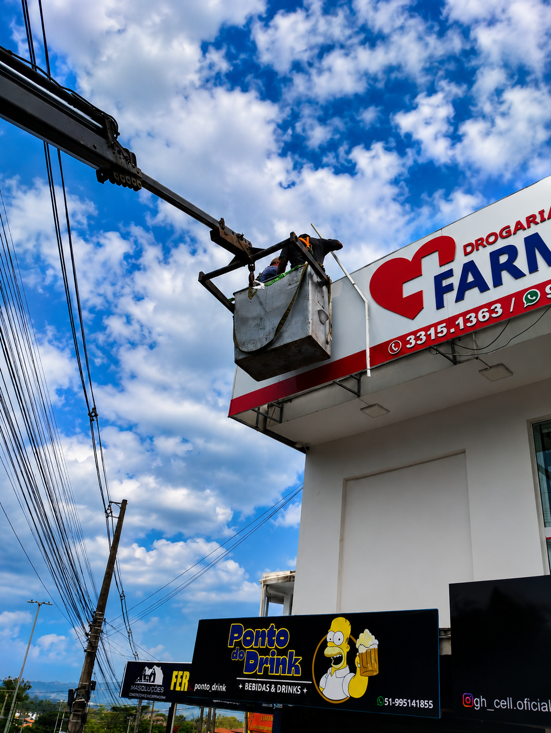 Guindaste elevando operador em manutenção de fachada de drogaria